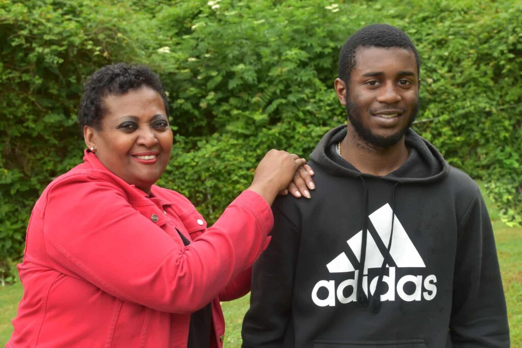 Woman posing with a teenage boy outside.
