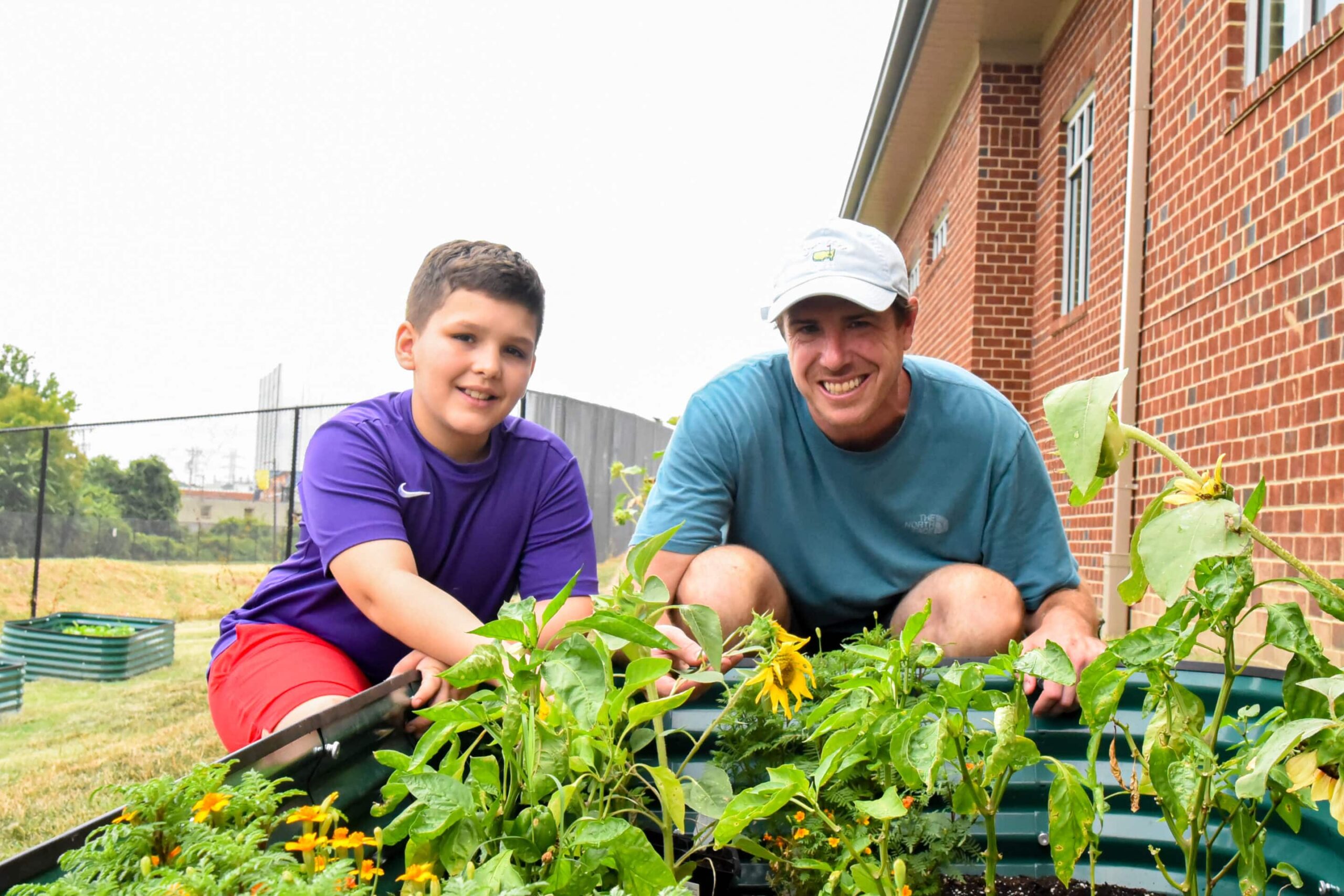 Man and a boy outside at a raised garden bed