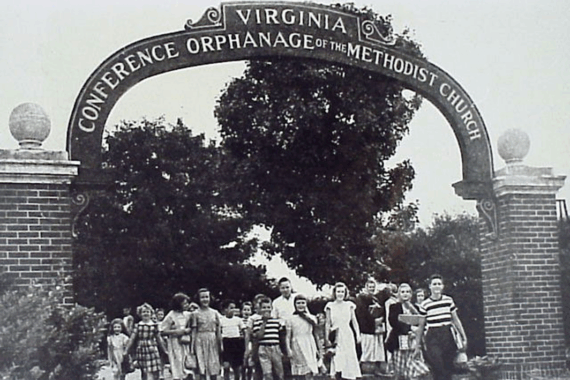 Children walking outside under an orphanage sign