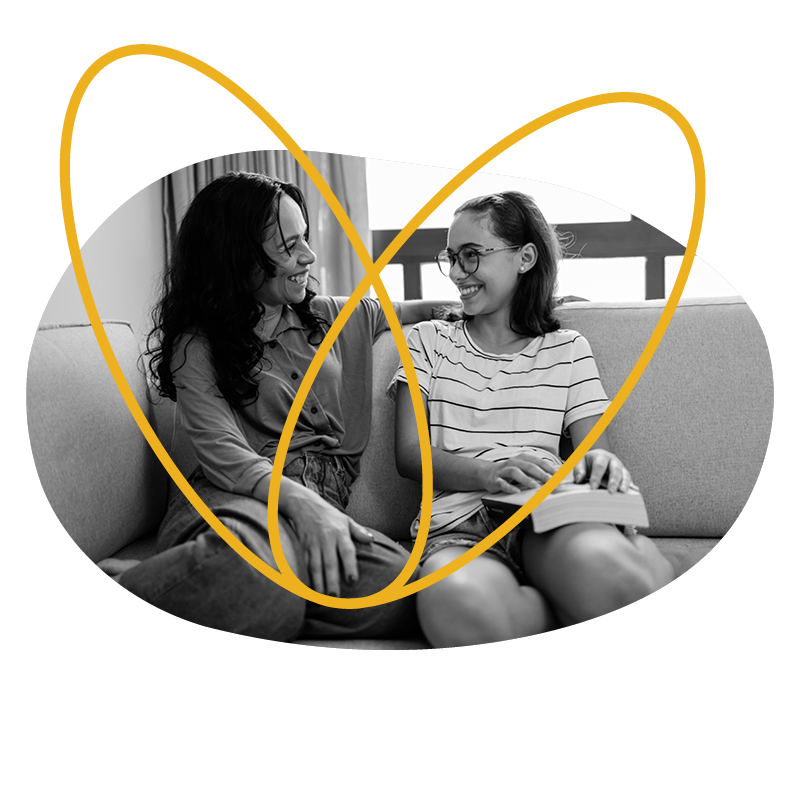 A woman and a girl sitting on a couch smiling at each other