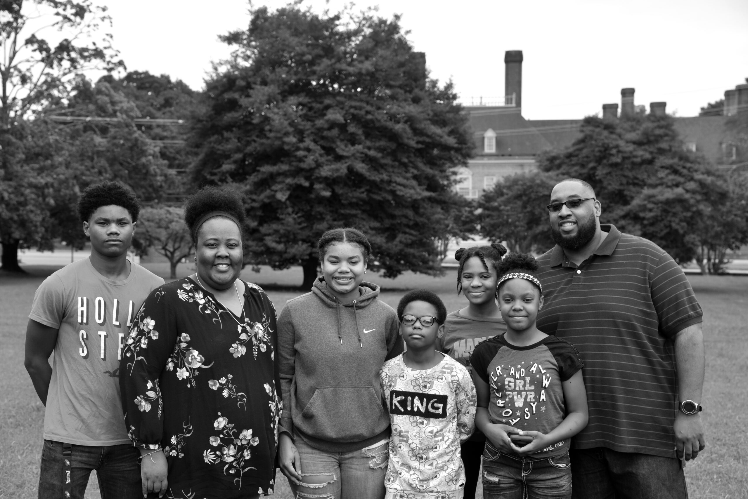 A man and a woman standing outside with 5 kids