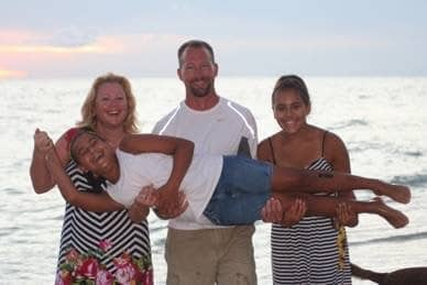 Kathleen and Matthew Palmer with kids, lizzy and emmy, standing on a beach.